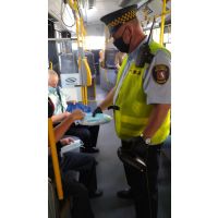 Strażnik miejski podaje maseczkę pasażerowi w autobusie MPK