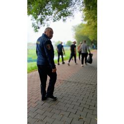 Funkcjonariusz Straży Miejskiej w tle sprzątający osadzeni