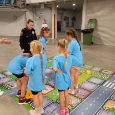 Dzieci na planszy wraz z funkcjonariuszką Straży Miejskiej