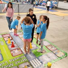 Dzieci na planszy wraz z funkcjonariuszką Straży Miejskiej