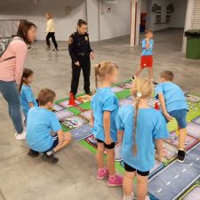 Dzieci na planszy wraz z funkcjonariuszką Straży Miejskiej